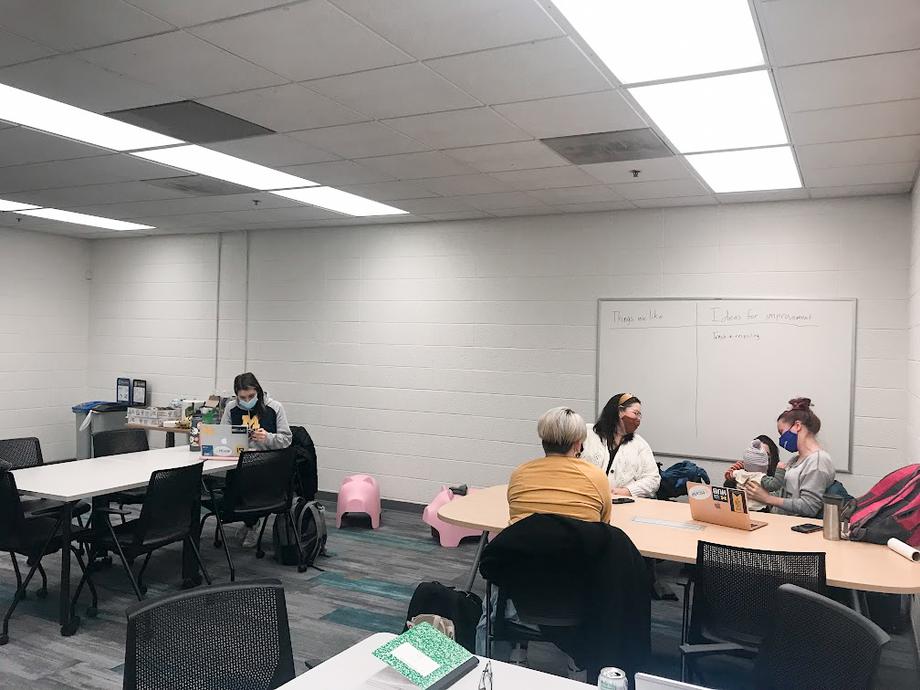 Student Parent and Caregiver Study Room with tables, chairs, five women and one child sitting down and talking/studying